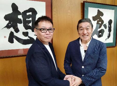 学校法人「国際志学園」の水嶋章陽理事長（右）と握手する「ＭＭＡ甲子園」を主催する岩崎ヒロユキ代表＝２０２５年７月、北九州市