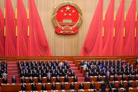 中国全人代が開幕し、国歌斉唱する代表＝５日、北京の人民大会堂（共同）