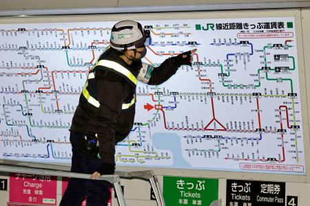 値上げが反映された運賃表を確認する作業員＝１４日未明、ＪＲ東京駅