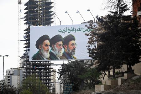 街頭に掲げられたイランの最高指導者モジタバ・ハメネイ師（右）らの肖像＝２０日、テヘラン（共同）