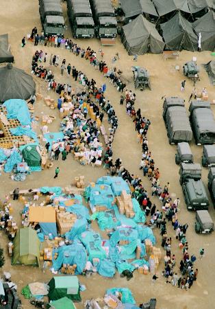 阪神大震災の避難所となった小学校の校庭で、救援物資の配給に並ぶ被災者の長い列＝１９９５年１月、神戸市東灘区