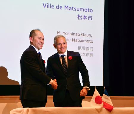握手する長野県松本市の臥雲義尚市長（左）とシャンボール国立公園トップのピエール・デュブルイユ氏＝１日午後、東京都港区