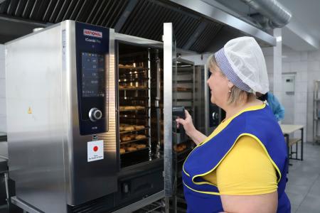 ２日、キーウの学校で、日本が供与したオーブンを使う調理担当者（共同）