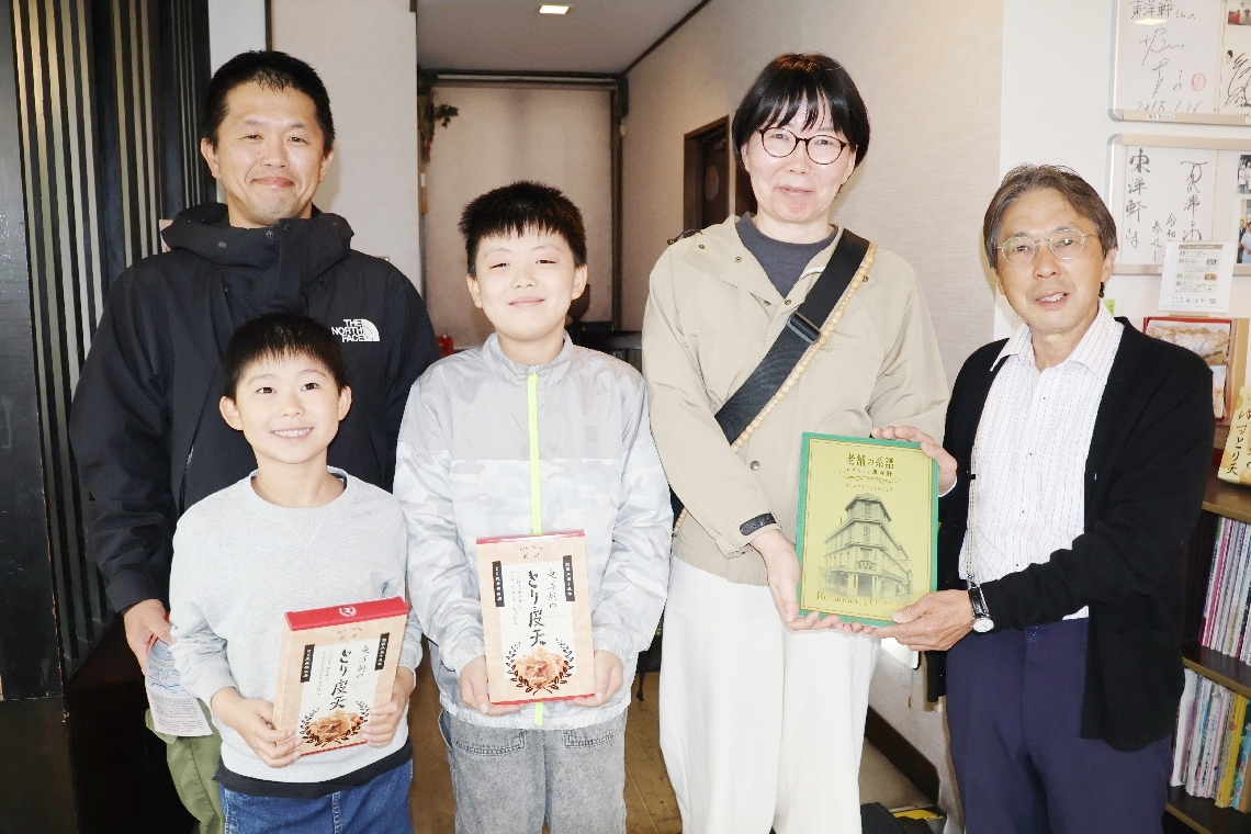 １００周年を迎え、最初に来店した家族に記念品を贈る３代目の宮本博之さん（右端）＝別府市石垣東の「レストラン東洋軒」