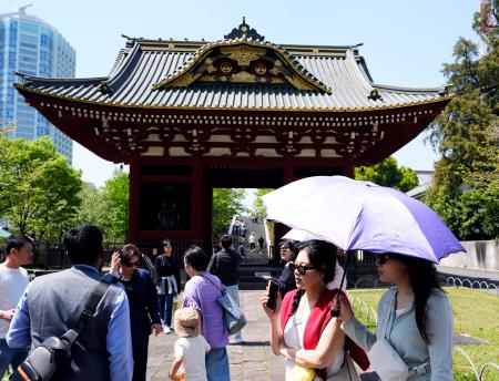 今年初の夏日となった東京都心部で日傘を差して歩く人たち＝１１日午後、東京都港区