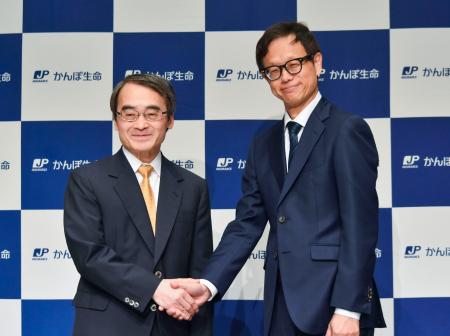 かんぽ生命保険の次期社長に内定している大西徹副社長（右）と握手する谷垣邦夫社長＝１３日午後、東京都千代田区