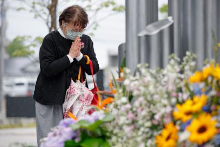 熊本地震の「前震」から１０年となり、震災記念公園で献花し手を合わせる女性＝１４日午前、熊本県益城町