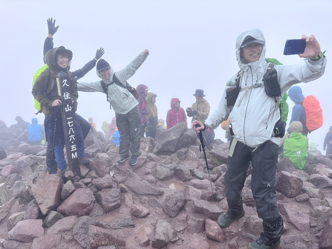 山頂で記念撮影する登山者