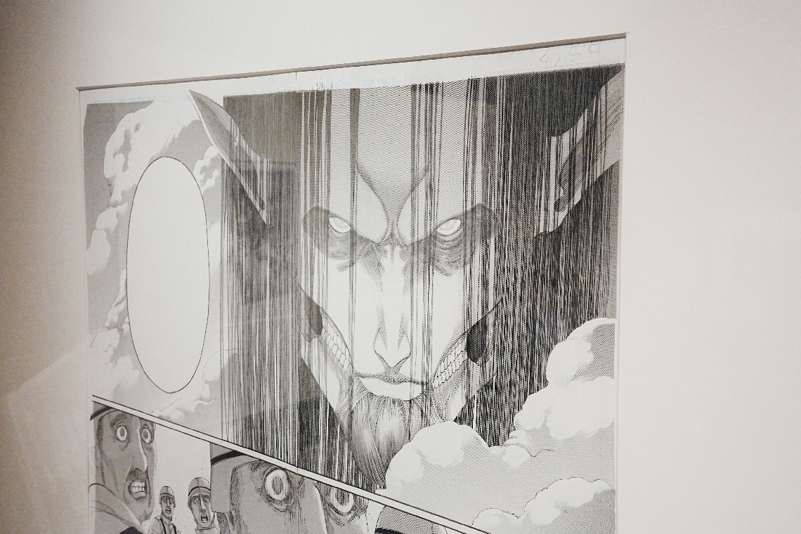 巨人の真っすぐな髪は諫山創さんの指示でアシスタントが描いた。「定規の直線では表現できない生物感が宿った」とコメントが添えられている