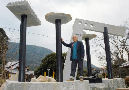「旧金毘羅大芝居」（左後方）の鉄柱を使いモニュメントを作った篠原勝之さん＝２００５年３月、香川県琴平町