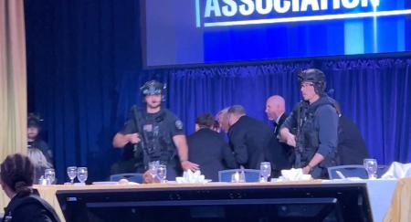 ２５日、ホワイトハウス記者会主催の夕食会会場から退避を促されるトランプ米大統領＝ワシントン（ロイター＝共同）