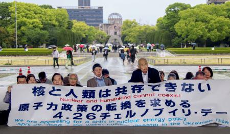 チョルノービリ原発事故から４０年を迎え、脱原発を訴えて座り込みを行う人たち＝２６日午後、広島市の平和記念公園