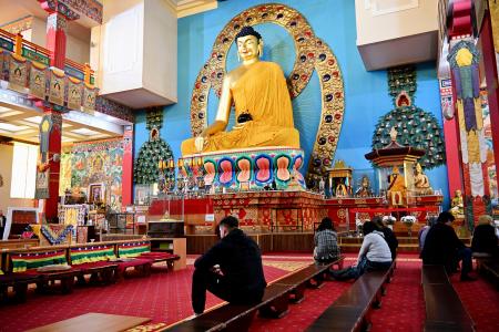 欧州最大とされるチベット仏教寺院にある仏像の前で祈る人ら＝３月、ロシア南部カルムイキア共和国エリスタ（共同）