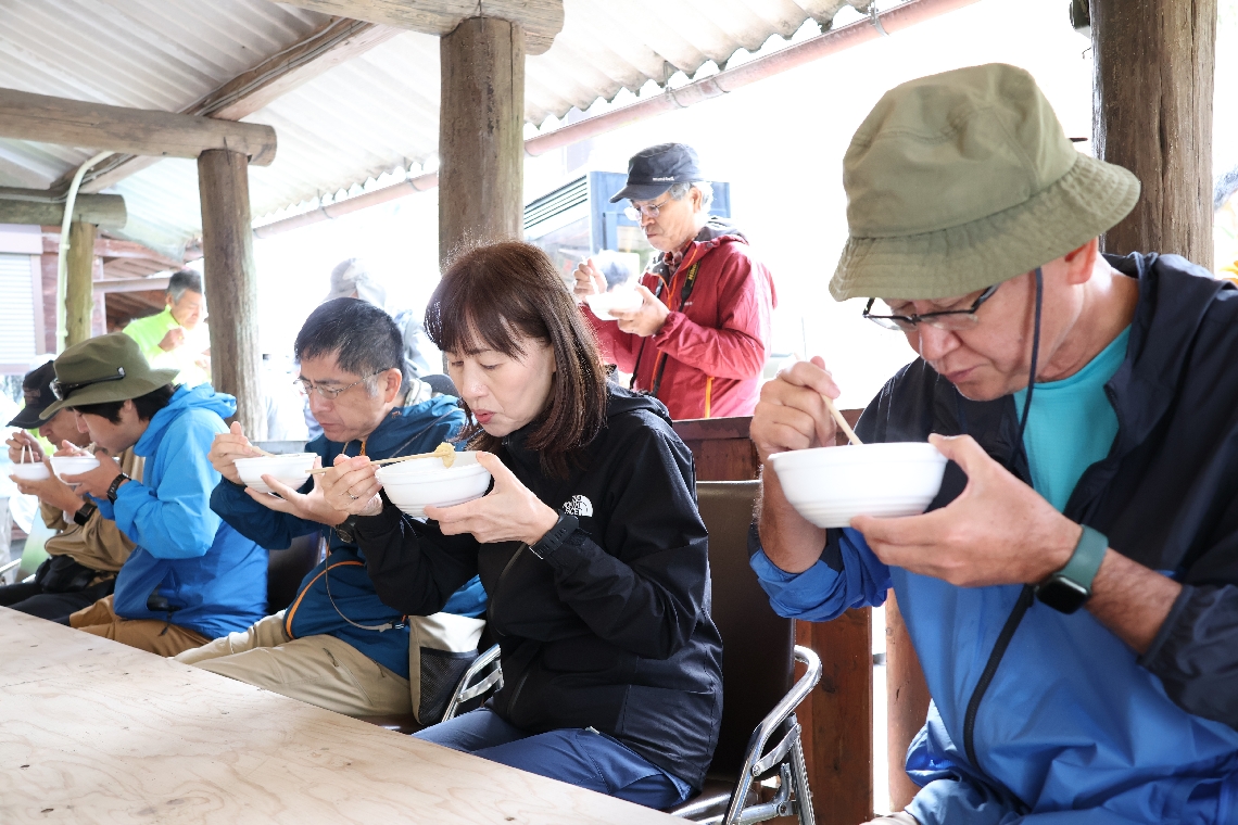 振る舞われた豚汁を食べる登山客ら