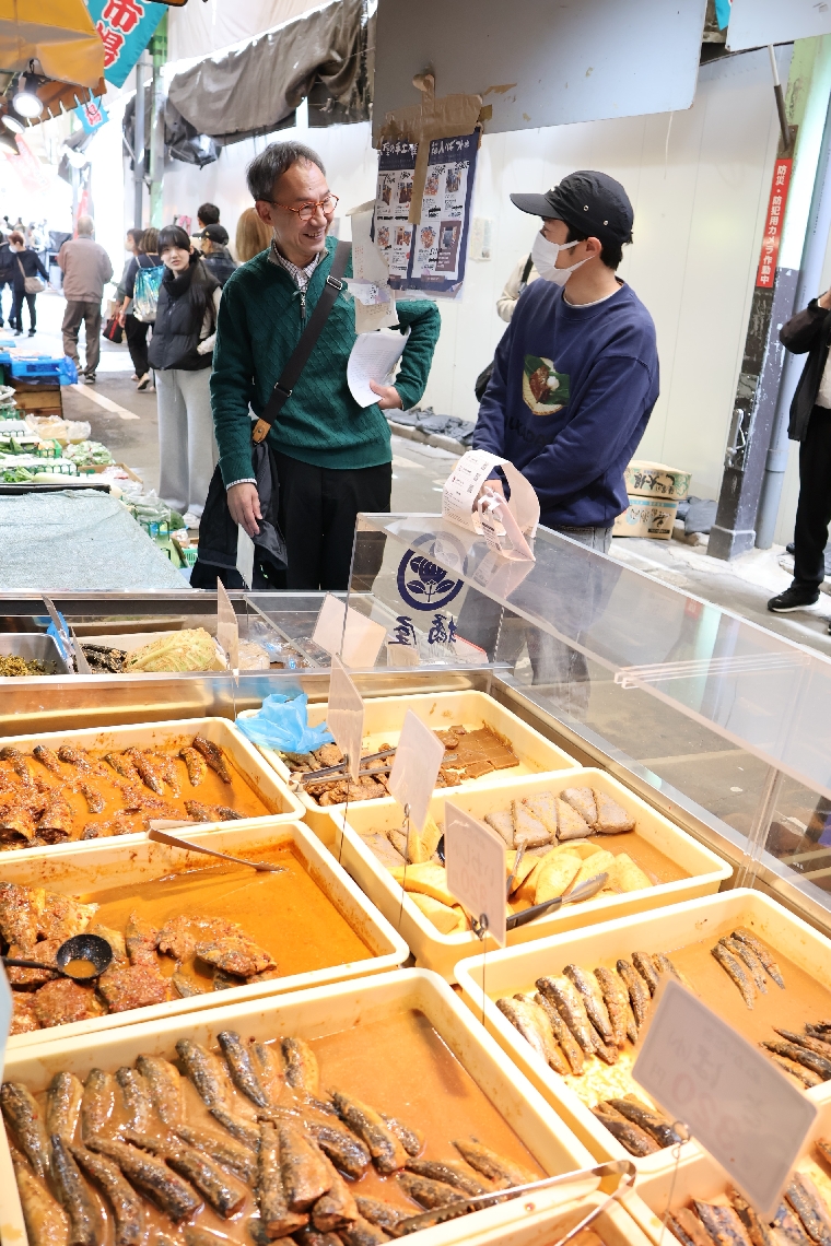 小倉名物「ぬか炊き」の店主（右）と打ち合わせをする臼杵市中央通り商店街振興組合の関係者＝４月、北九州市小倉北区
