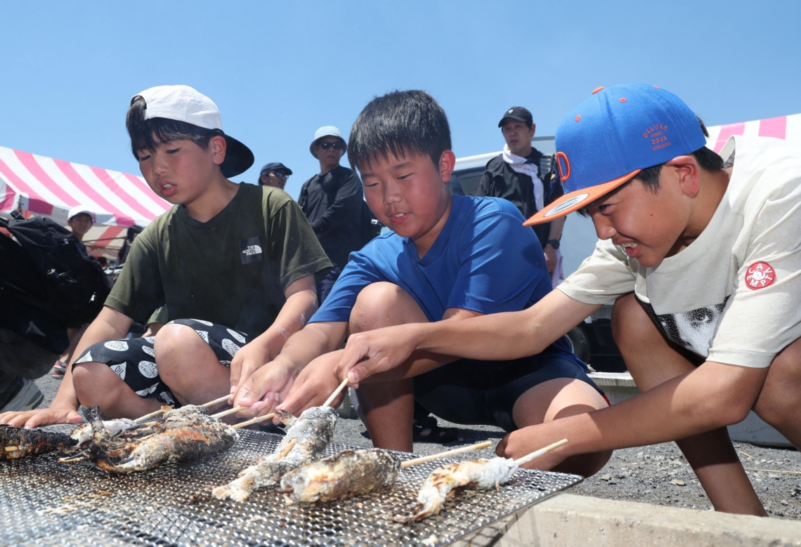 自分で捕まえた魚を焼く子どもたち＝玖珠町の玖珠川河川敷