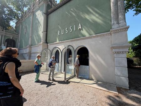 ロシア館に入れず、屋外から映像を見る来場者＝９日、イタリア・ベネチア（共同）