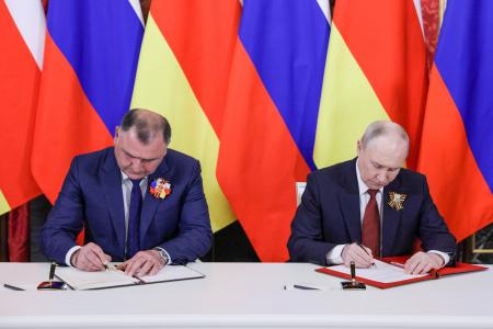 ９日、モスクワで同盟協力深化に関する条約に署名するロシアのプーチン大統領（右）と南オセチアのトップ、ガグロエフ氏（ロシア大統領府提供・タス＝共同）
