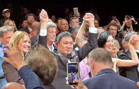 カンヌ国際映画祭で「急に具合が悪くなる」の公式上映後、手をつないで喜びの表情を見せる（左から）ビルジニー・エフィラさん、濱口竜介監督、岡本多緒さん＝１５日、フランス・カンヌ（共同）