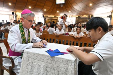 マニラ首都圏ケソン市の教会で、折り鶴を作るブラウン大司教（手前左）＝１６日（共同）