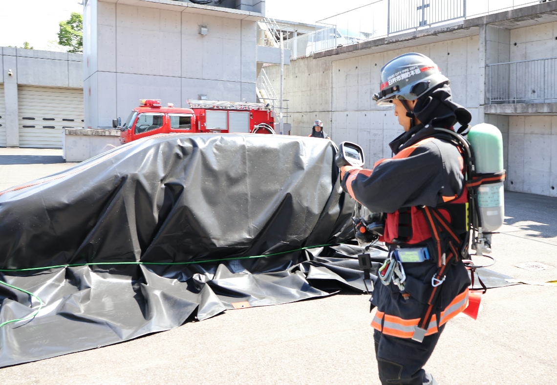 消火用ブランケットをかぶせた車両の熱を確認する臼杵市消防署の隊員