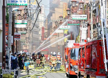 大阪市中央区の火災現場で、消火活動する消防隊員ら＝１８日午前８時３５分