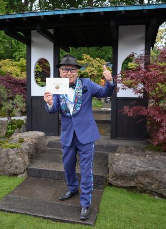 自身がデザインした庭園を背景にポーズをとる石原和幸さん＝１９日、ロンドン（共同）