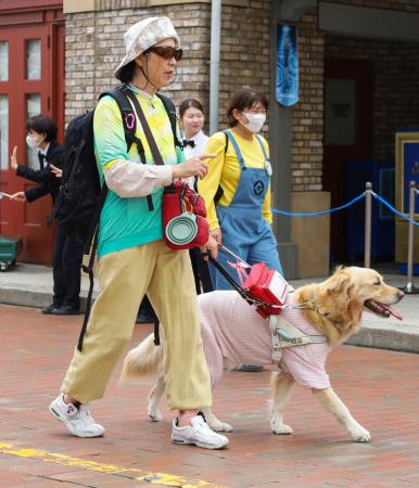 靴に振動型の道案内デバイスを装着してＵＳＪのパーク内を歩く満田育代さん（左）＝２２日午前、大阪市