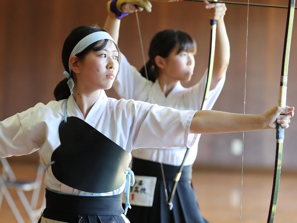 最後の１本を引き終え、まっすぐ的を見つめる雄城台の阿南（手前）＝大洲弓道場、撮影・首藤福功