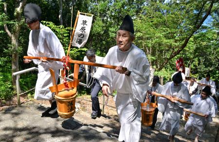 山神社で営まれた「献湯祭」で、朝一番の源泉からくみ上げた「一番湯」を運ぶ関係者ら＝１日午前、和歌山県白浜町