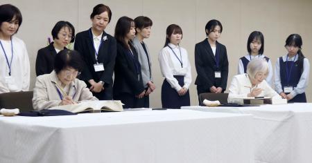 原爆死没者名簿に記帳する中本信子さん（手前左）と大川純子さん。後方は一般公募で選ばれた記帳者ら＝４日午前、広島市役所