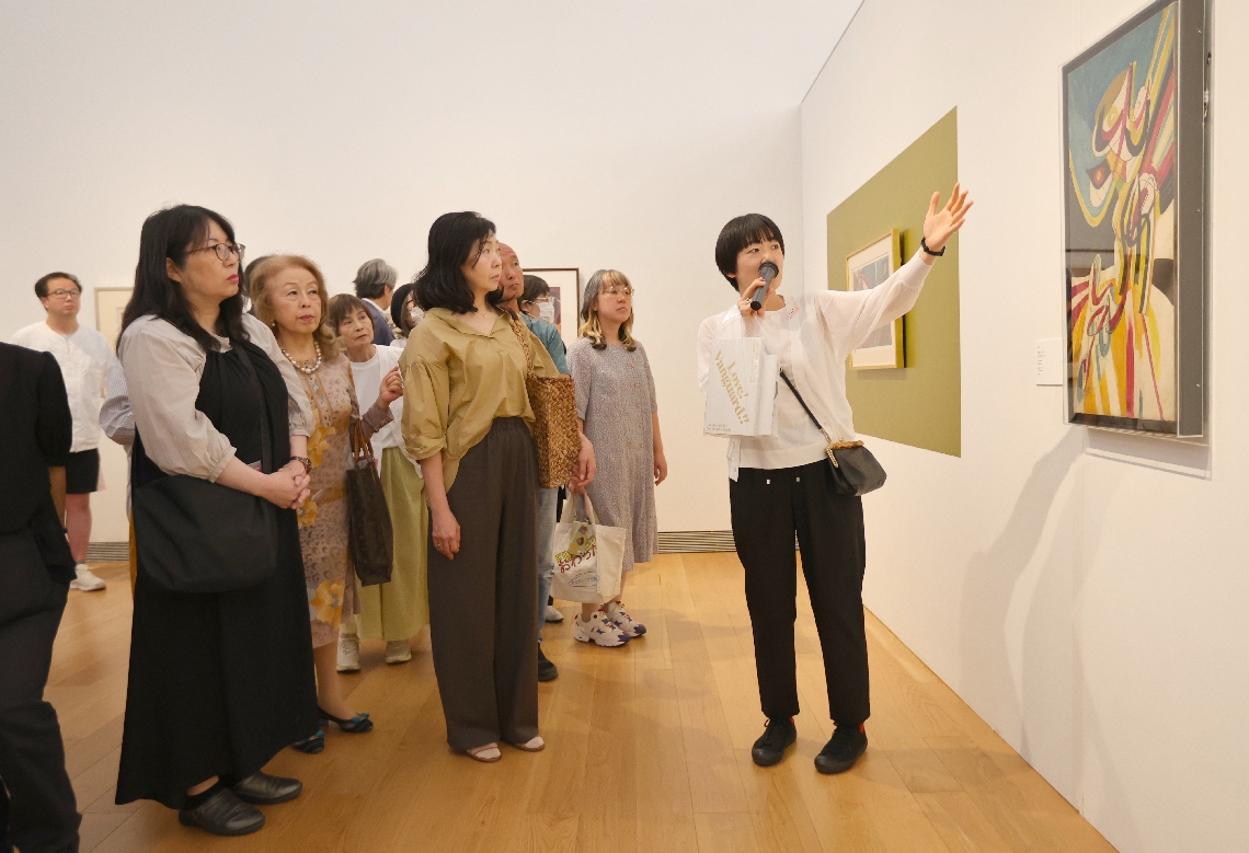 学芸員の説明を聞きながら展示作品を見る来場者