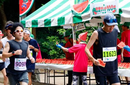 「富里スイカロードレース」で、スイカを食べるランナー＝１４日午前、千葉県富里市