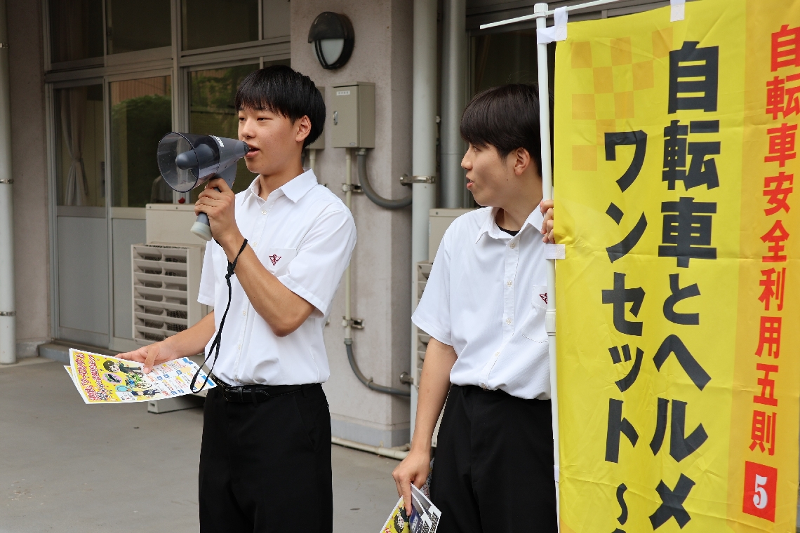 拡声器を使い「ヘルメットを着用しましょう」と呼びかける生徒