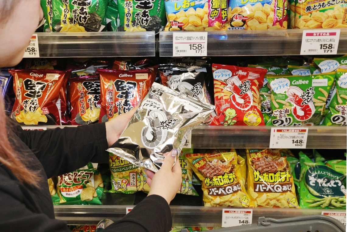 白黒パッケージのかっぱえびせんを手に取る買い物客＝１９日、大分市古国府のサンライフアップル