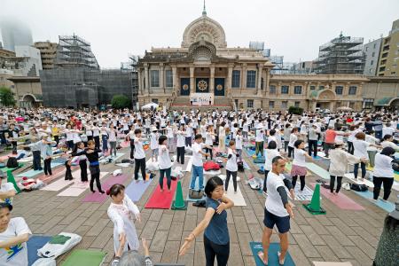 国連が定めた「国際ヨガの日」に、東京都中央区の築地本願寺の境内でヨガを楽しむ参加者＝２１日午前