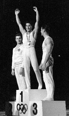 １９６４年１０月、東京五輪体操男子種目別の跳馬で金メダルを獲得した松田（旧姓山下）治広さん（中央）＝東京体育館