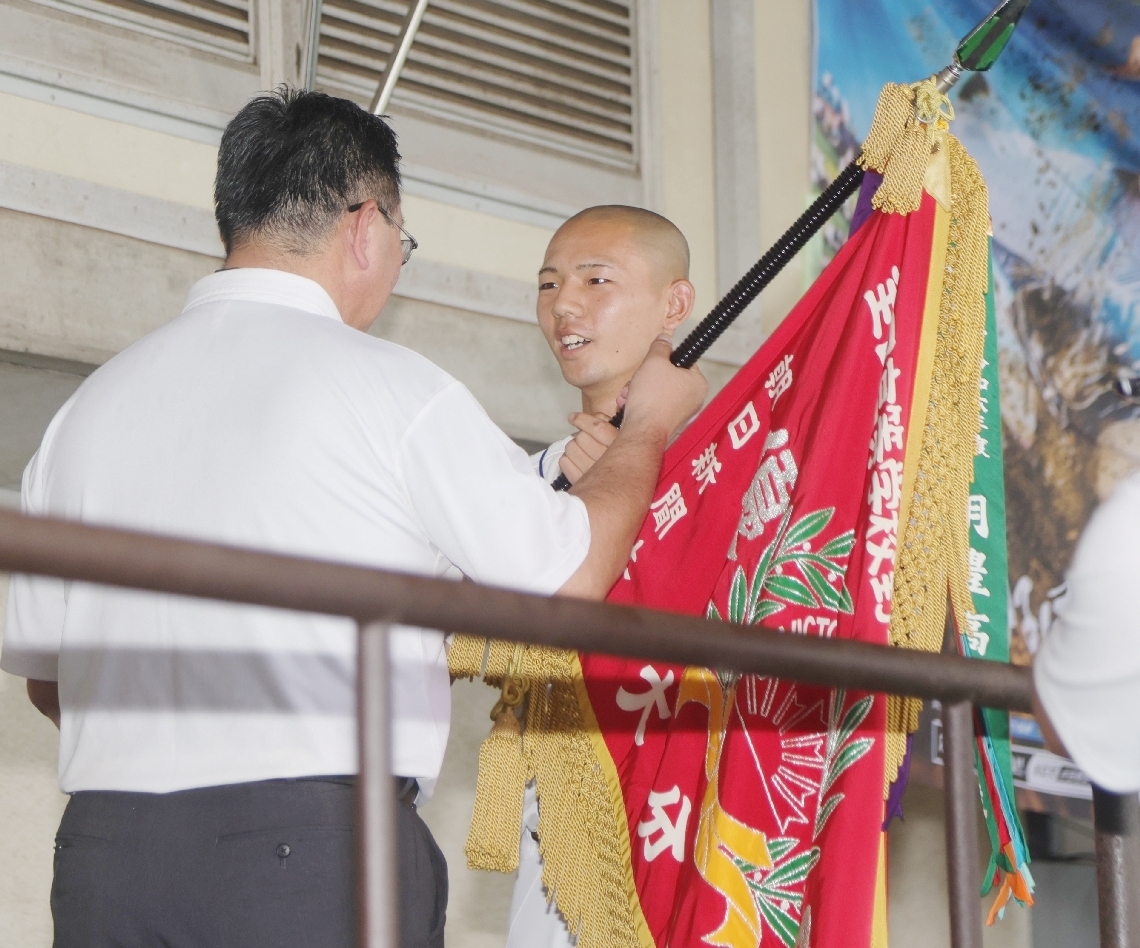 優勝旗を返還する明豊の坂田主将（右）