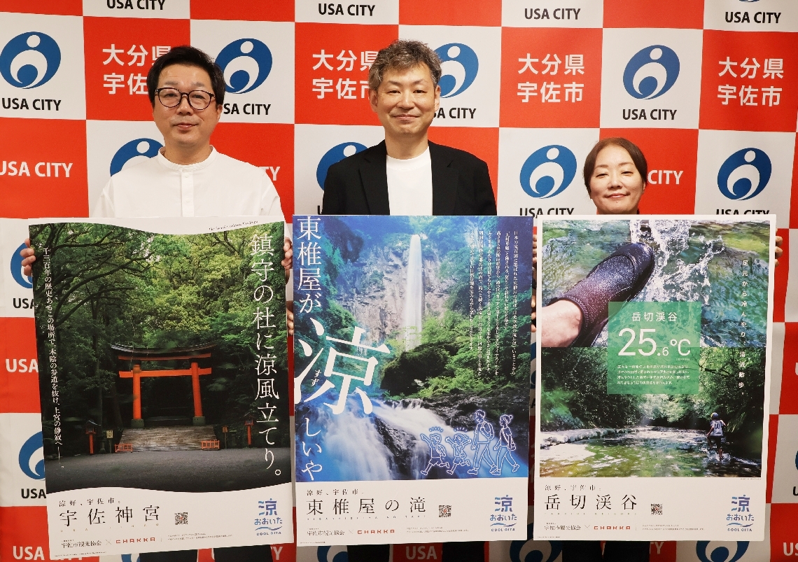 完成したポスターを披露するＣＨＡＫＫＡの青山正樹代表（中央）ら＝宇佐市役所