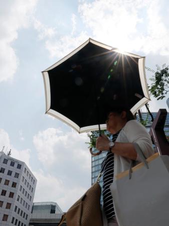 強い日差しの中、福岡市の繁華街で日傘を差して歩く人。九州北部が梅雨明けした＝８日午後