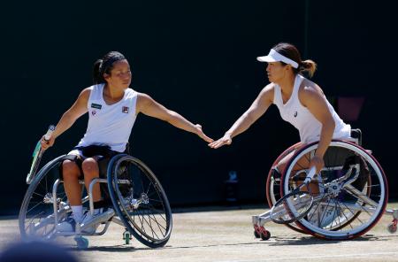 車いすの部女子ダブルス決勝でポイントを奪いタッチを交わす上地結衣（左）、朱珍珍組＝ウィンブルドン（共同）