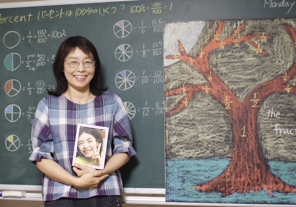 シュタイナー教育や英語を取り入れたフリースクールを主宰するソーンダーズ首藤佳代さん。手にする写真は英子さん＝大分市
