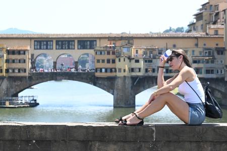 イタリア中部フィレンツェの観光名所、ベッキオ橋付近で涼を取る観光客＝１４日（ゲッティ＝共同）