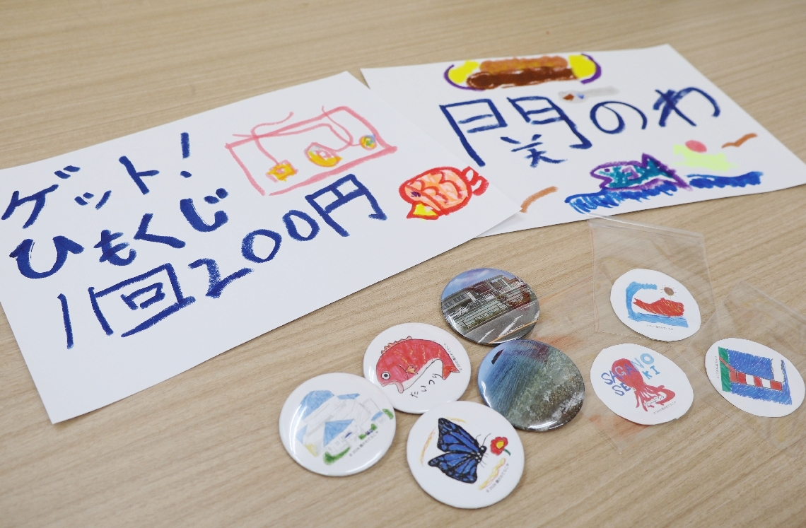 「ひもくじ」の景品になる佐賀関をモチーフにしたイラストの缶バッジやシール