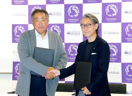 ソフトバンクの常務執行役員（左）と握手する東北大の越村俊一教授＝２７日午後、東京都港区