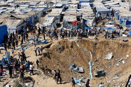 イスラエル軍の攻撃があった医薬品の倉庫の様子を見る人たち＝１日、ガザ中部デールバラハ（ロイター＝共同）