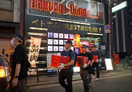 ベトナム人向け店舗が入るビルを家宅捜索した大阪府警の捜査員＝４日、大阪市中央区