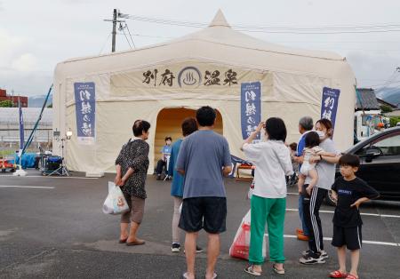 移動型温泉施設「幻想の湯」に並ぶ被災者ら＝７日午後、熊本県八代市