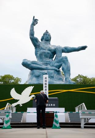 被爆から８１年の原爆の日を迎え、平和祈念像の前で手を合わせる人＝９日早朝、長崎市の平和公園