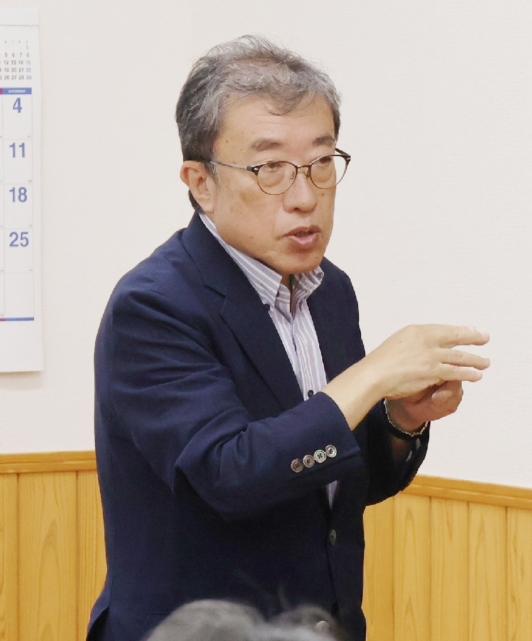防空壕に刻まれた文字について、地域住民に報告する藤井通彦さん＝大分市小佐井